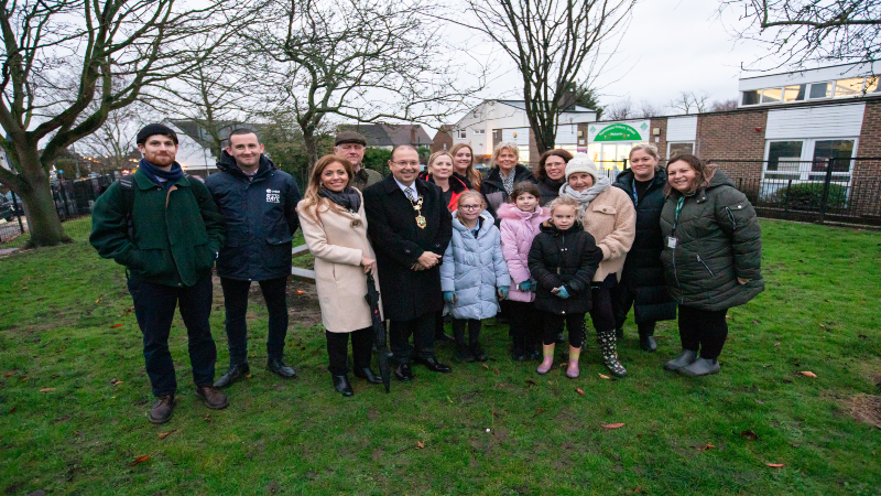 Group of people including the Mayor and Cllr Seymour on grass land outside a school.