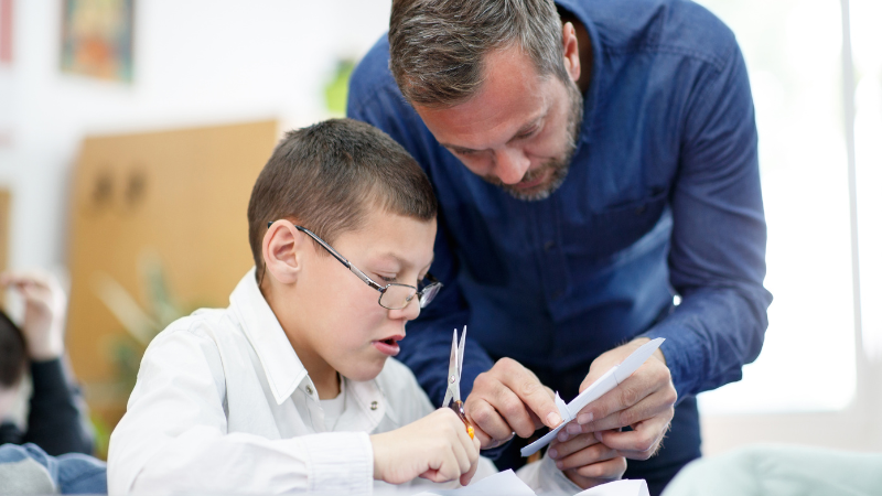 Image of a school age child being supported by a teacher.